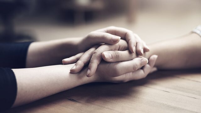 Holding hands at wood table small overlay